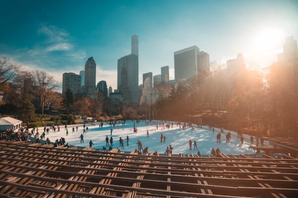 Viele Menschen sind bei strahlendem Sonnenschein auf der Eisfläche im Central Park
