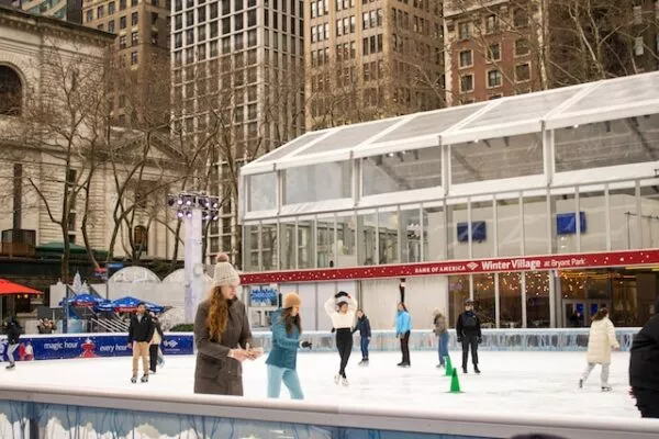 Das Winter Village am Bryant Park mit großer Eisfläche, auf der mehrere Menschen Schlittschuh fahren