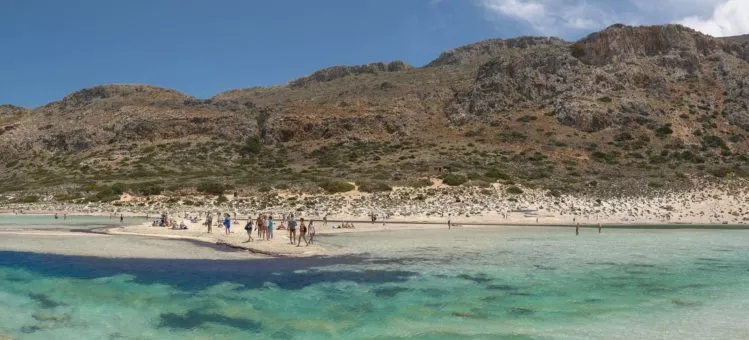 Menschen am Sandstrand vor türkisfarbenen Wasser