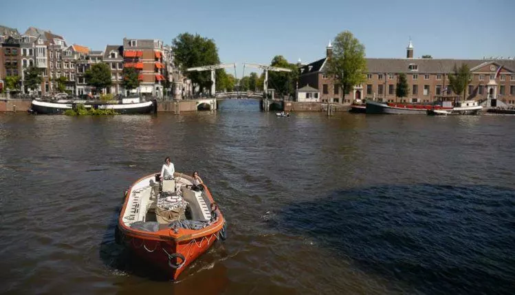 Kleines Motorboot auf Gracht in Amsterdam