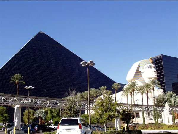 Vor der im Sonnenlicht schwarz erscheinenden Pyramide des Luxor Hotels steht eine Nachbildung der Sphinx