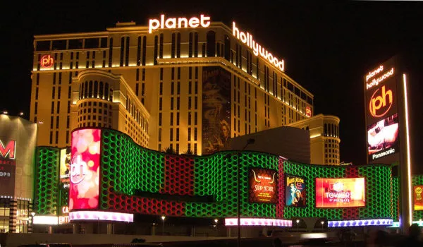 Das Planet Hollywood Hotel leuchtet in der Nacht hinter einer großen Reklametafel
