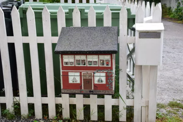 Ein detailliert bemalter Briefkasten hängt an einem weißen Zaun