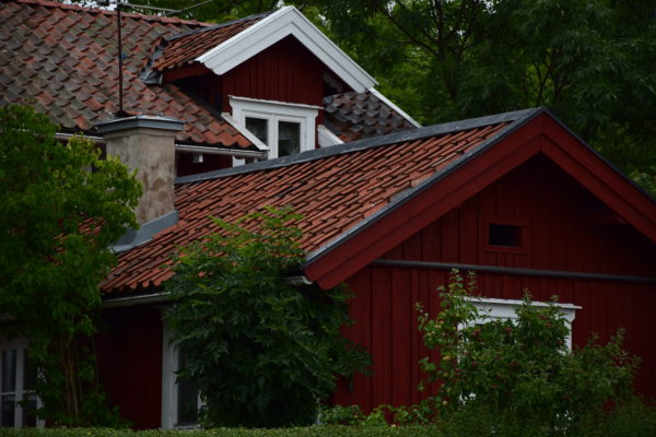 Das Dach einer roten Holzhütte ragt über die Baumwipfel