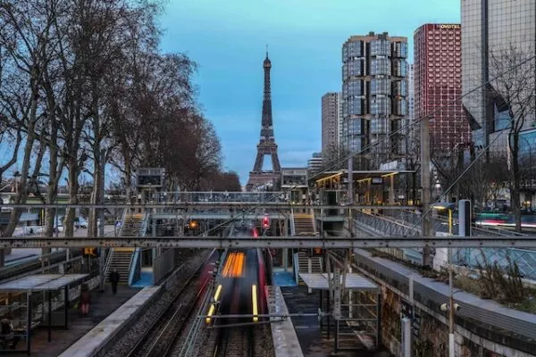 Im Hintergrund der Eiffelturm, davor ein Bahnübergang über der Pariser Metro