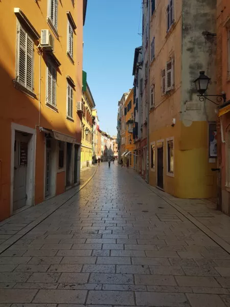 Eine gepflasterte Straße, die zwischen gelben Häusern entlangführt