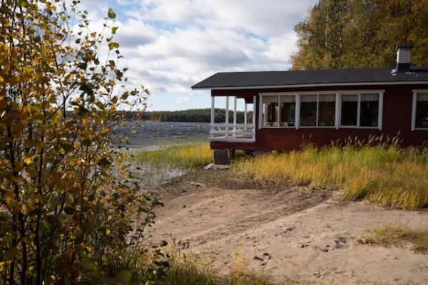 Eine rote Hütte steht direkt am Ufer eines finnischen Gewässers 