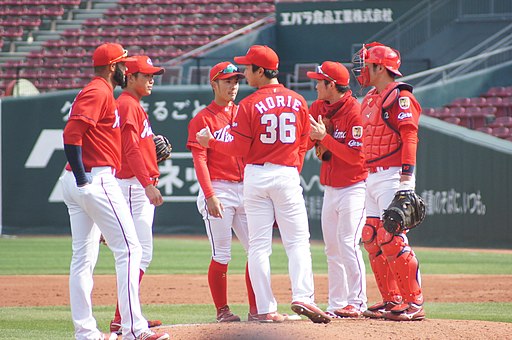 Eine Gruppe Baseballspieler in roten Shirt uns weißen Hosen auf einem Spielfeld