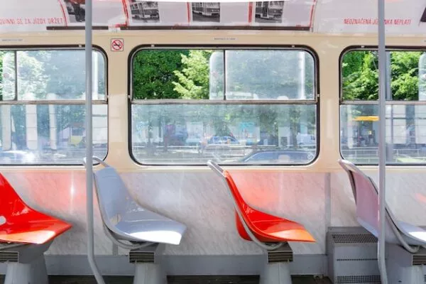 Blick auf eine Stuhlreihe im Inneren einer Tram hinaus auf die Straße im Sommer