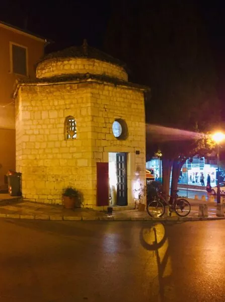 Ein kleines, siebeneckiges Gebäude aus Stein bei Nacht, essen Tür offen steht und aus der es leuchtet