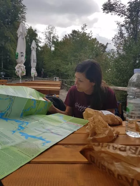 Eine Person sitzt an einem Tisch und schaut auf eine Karte der Plitvicer Seen. Auf dem Tisch steht Proviant.