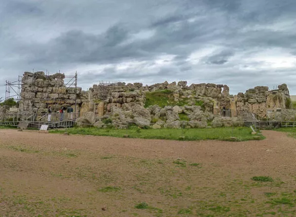 Auf einer nur leicht begrünten Fläche stehen alte Ruinen aus Stein 