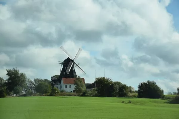 Eine Windmühle und ein Haus stehen in Mitten eines schwedischen Feldes