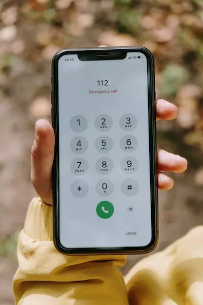 Jemand hält ein Smartphone mit Tastaturanzeige in der Hand, ganz oben auf dem Display steht "112 Emergency call"