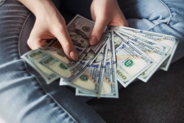 Eine Person hält mehrere US-Dollar-Scheine aufgefächert in ihren Händen